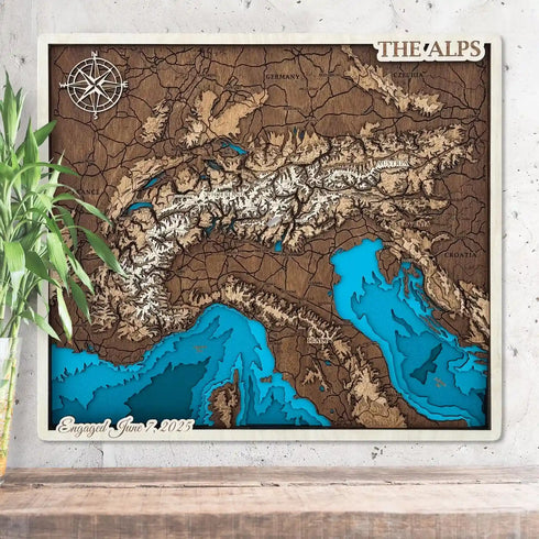 3D wooden map of The Alps with layered mountain contours and snowy peaks