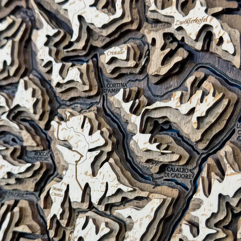 Close-up of carved wooden Dolomites map highlighting valleys and peaks.