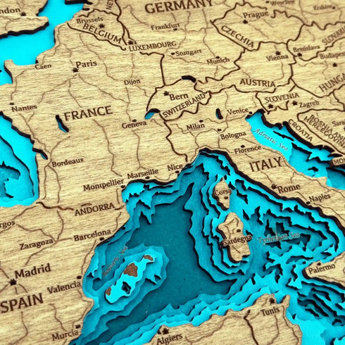 Close up of round Europe wooden map with engraved details and water layers
